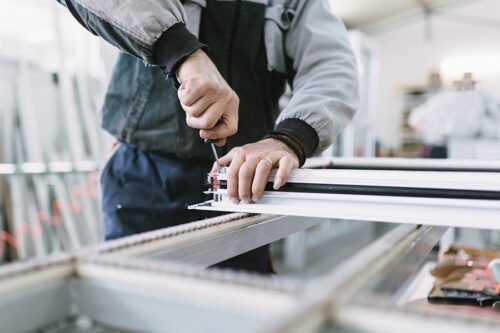 Une personne utilise un tournevis pour assembler ou ajuster un cadre métallique dans un atelier.